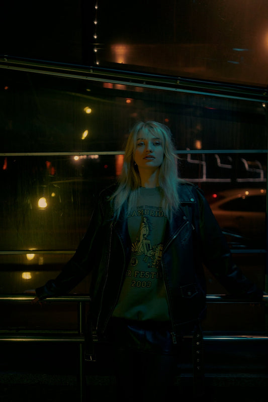 Woman in leather jacket at night with city lights